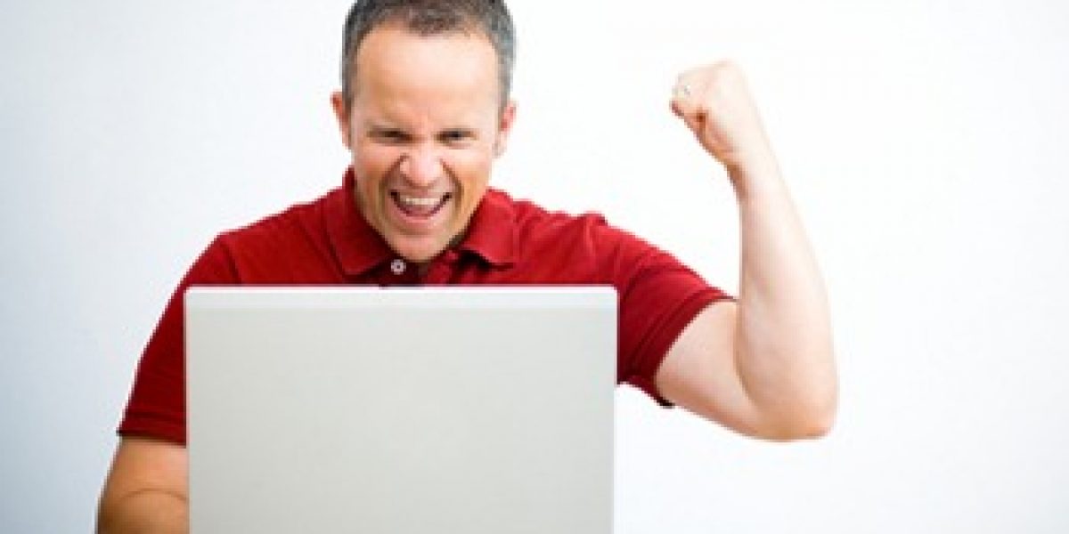 person looking at a laptop with fist raised in triumph